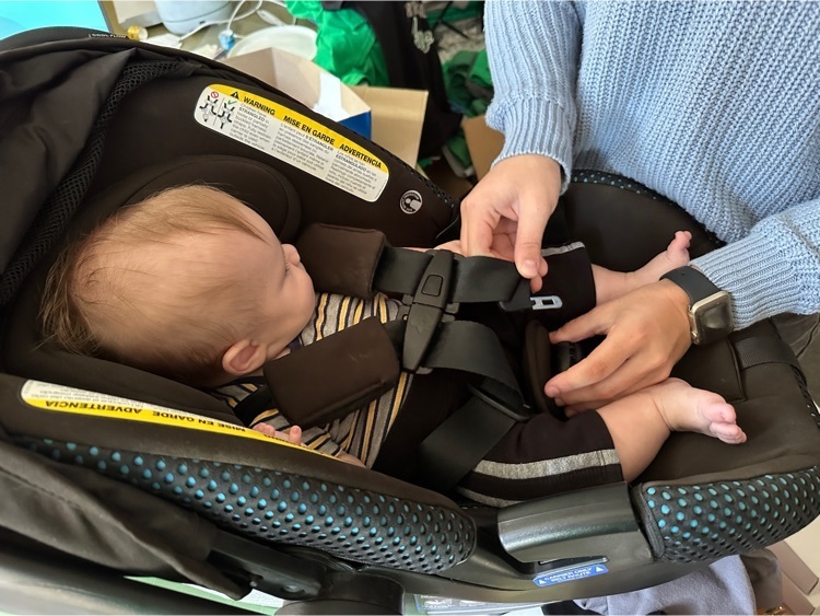 Student clipping the chest strap of a baby in a car seat